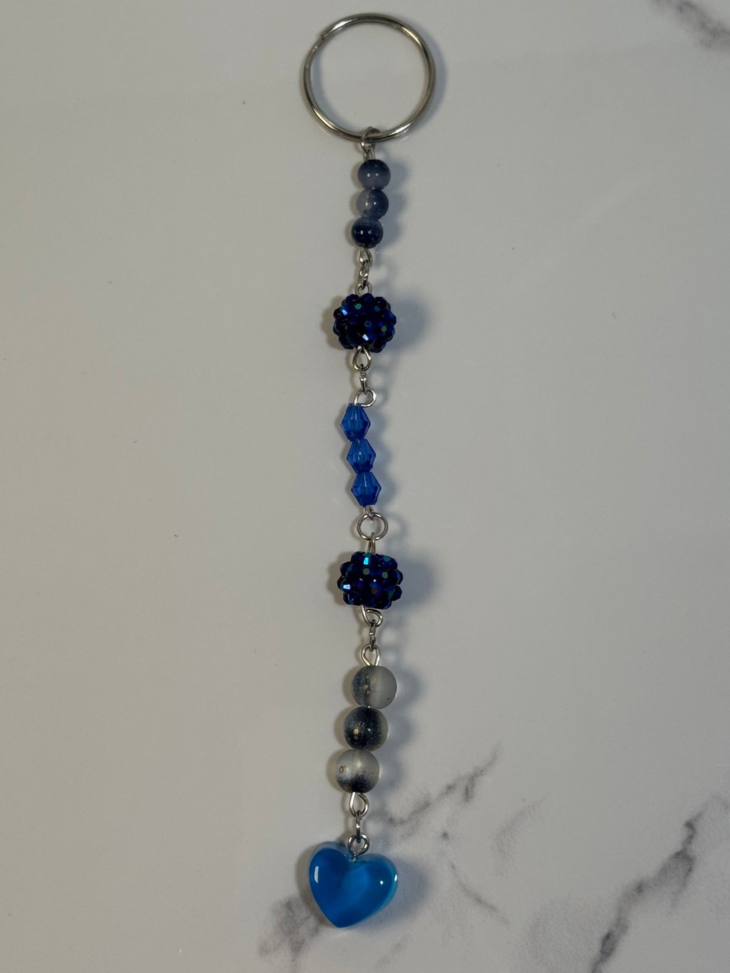Keychain with blue heart charm on a marble surface
