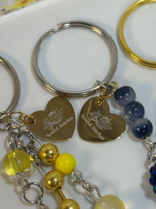 Collection of keychains with heart-shaped tags and colorful beads on a white surface
