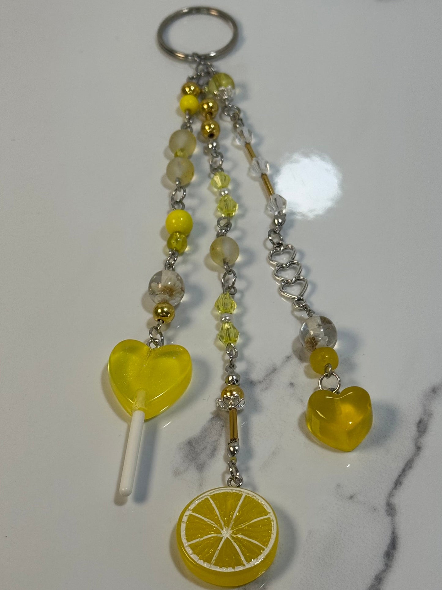 Yellow keychain with heart and lemon design on a marble surface