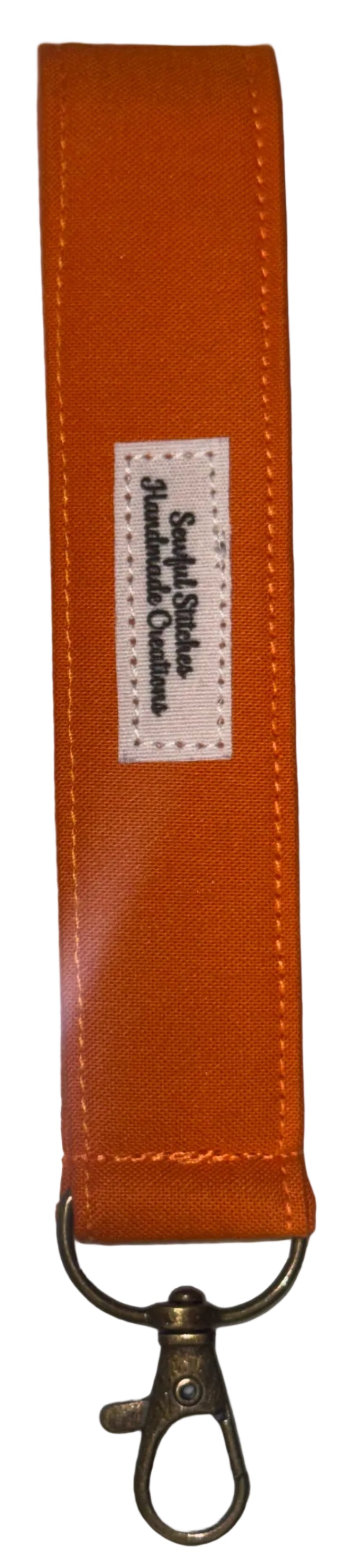 An orange keychain strap with a white brand label and a brass-colored lobster clasp, shown on a white background.