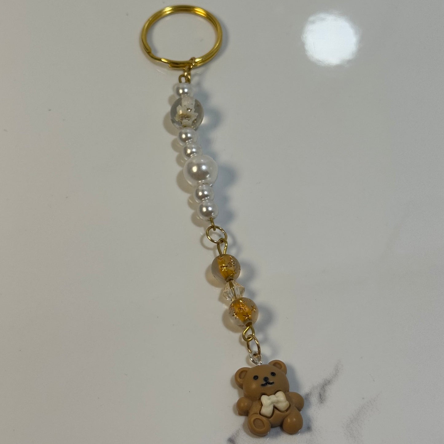 Keychain with beads and a small bear charm on a marble surface